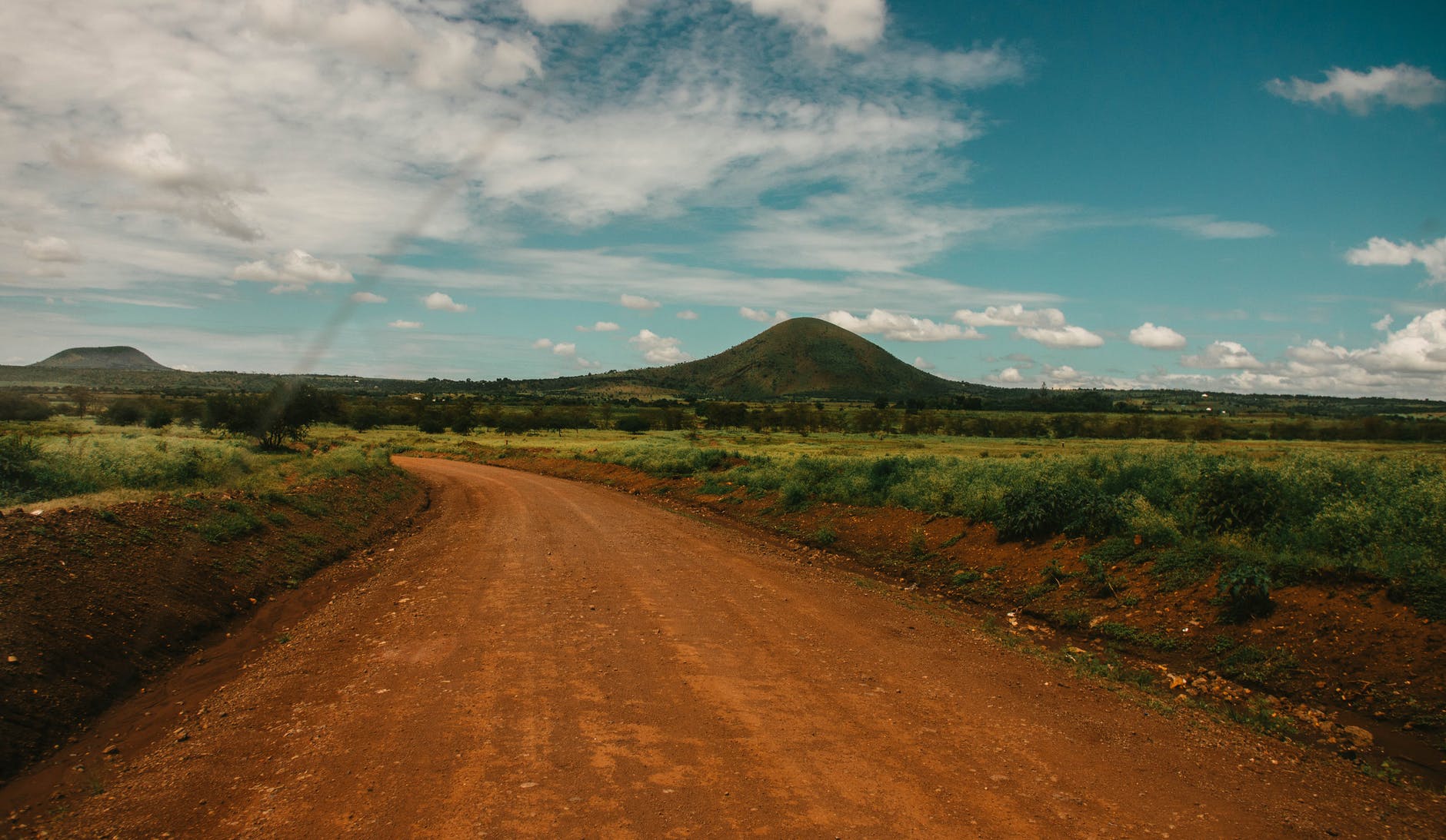 photo of dirt road across hill under cloudy sky